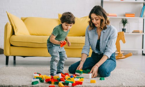 Mother and son playing with lego on carpet in living room